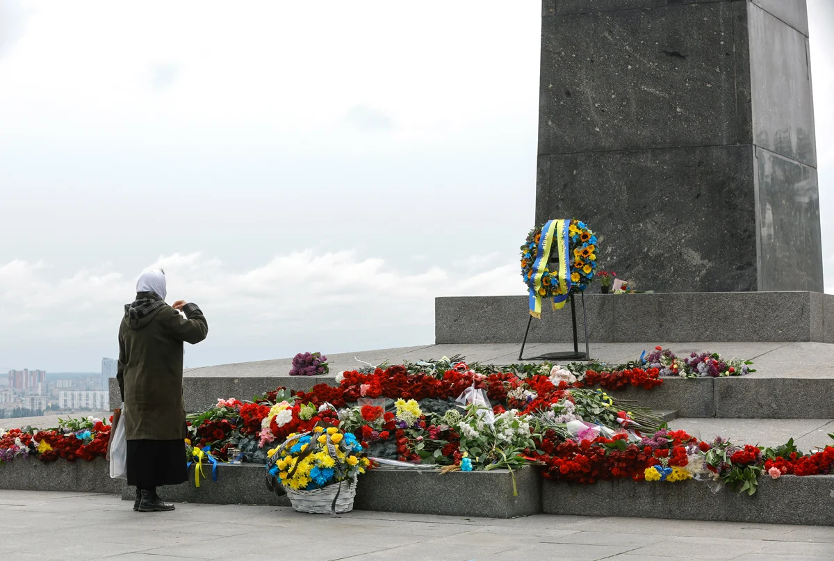 Женщина возлагает цветы к памятнику Неизвестному солдату в Киеве, 9 мая 2025 года. Фото: Sergey Dolzhenko / EPA