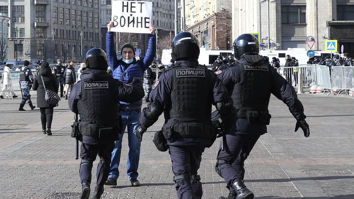 Сотрудники российской полиции бегут, чтобы задержать мужчину с плакатом с надписью: "Нет войне" во время несанкционированной акции протеста на Манежной площади перед Кремлем в Москве, 13 марта 2022 года. Фото: Contributor / Getty Images