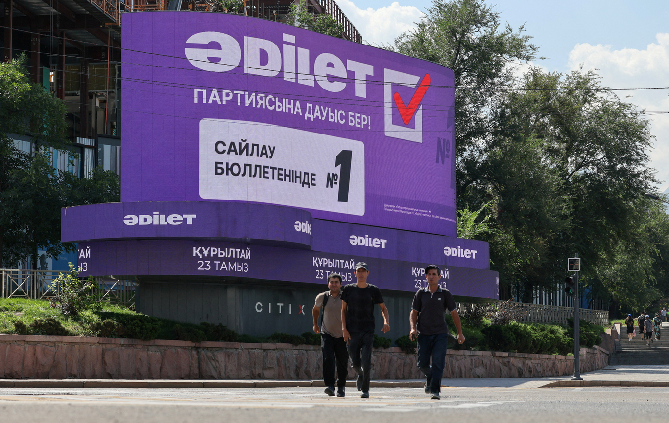 Прохожие на фоне экрана с рекламой партии «Адилет» в преддверии досрочных парламентских выборов. Алматы, Казахстан. 17 августа 2026 года. Архивное фото. Фото: Pavel Mikheyev / Reuters / Scanpix / LETA