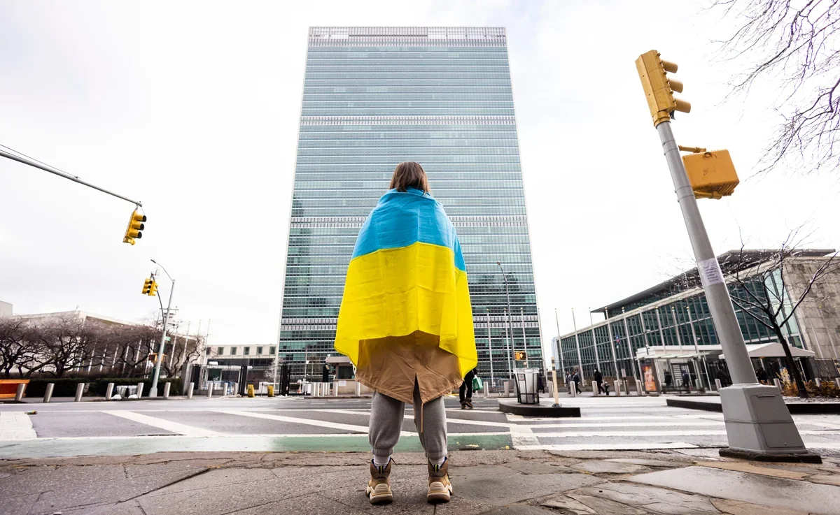 A woman with a Ukrainian flag stands in front of the UN headquarters, New York, 25 February 2022. Photo: Justin Lane / EPA