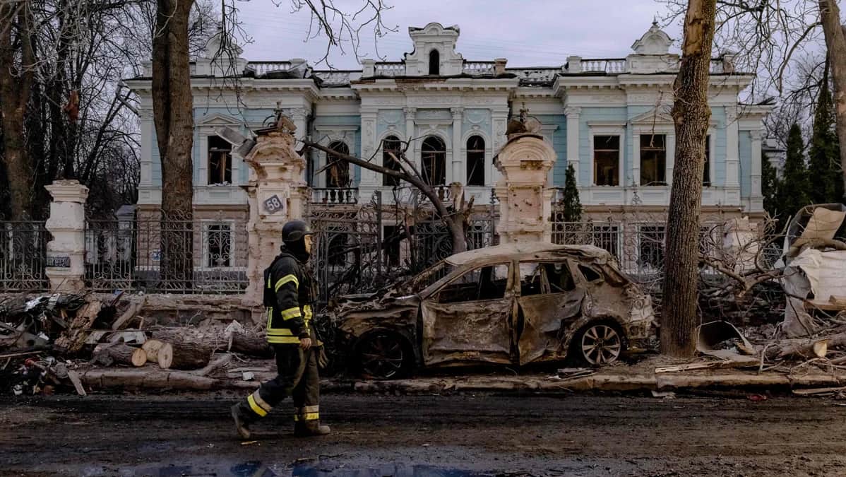 A rescue worker walks past a burnt-out car in front of a damaged building after a ballistic missile strike in Sumy, Ukraine 13 April 2025. Photo: Roman Pilipey / AFP / Scanpix / LETA