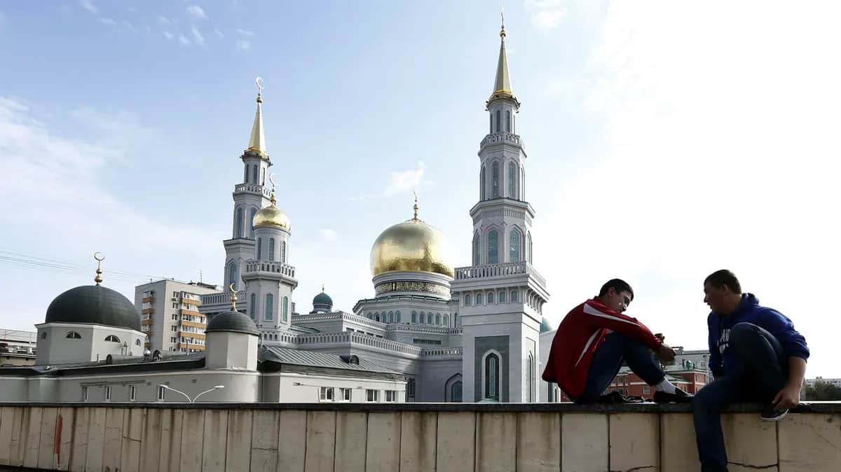 Two young people sit on a wall near Moscow’s Central Sobornaya Mosque. Photo: EPA/MAXIM SHIPENKOV