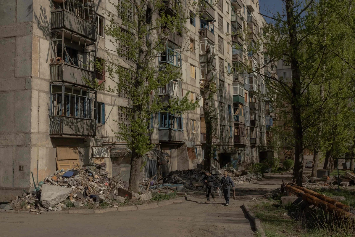 Люди на фоне поврежденных в результате авиаударов жилых домов в Константиновке, 20 апреля 2025 года. Фото: Roman Pilipey / AFP / Scanpix / LETA