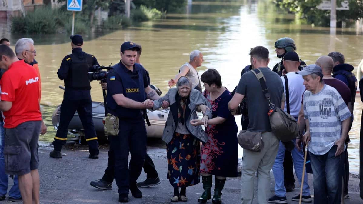 A police officer helps an elderly woman being evacuated from a flooded area of Kherson, 7 June 2023. Photo: Alexander Gimanov / AFP / Scanpix / LETA