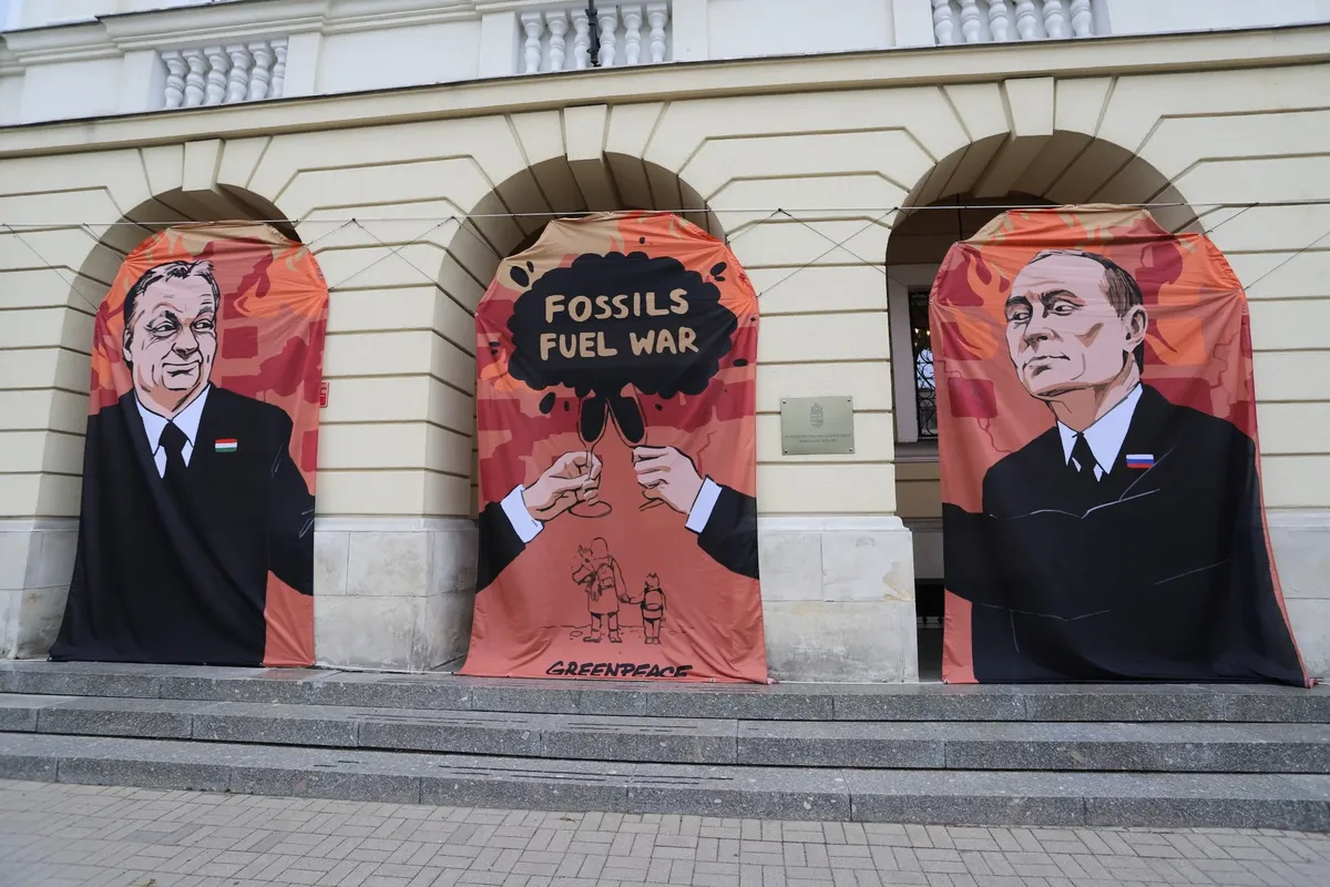 Баннер с изображением Виктора Орбана и Владимира Путина и лозунгом «Ископаемые — топливо войны» во время акции Greenpeace с требованием бойкота российской нефти перед посольством Венгрии в Варшаве, 25 мая 2022 года. Фото:<br>EPA-EFE