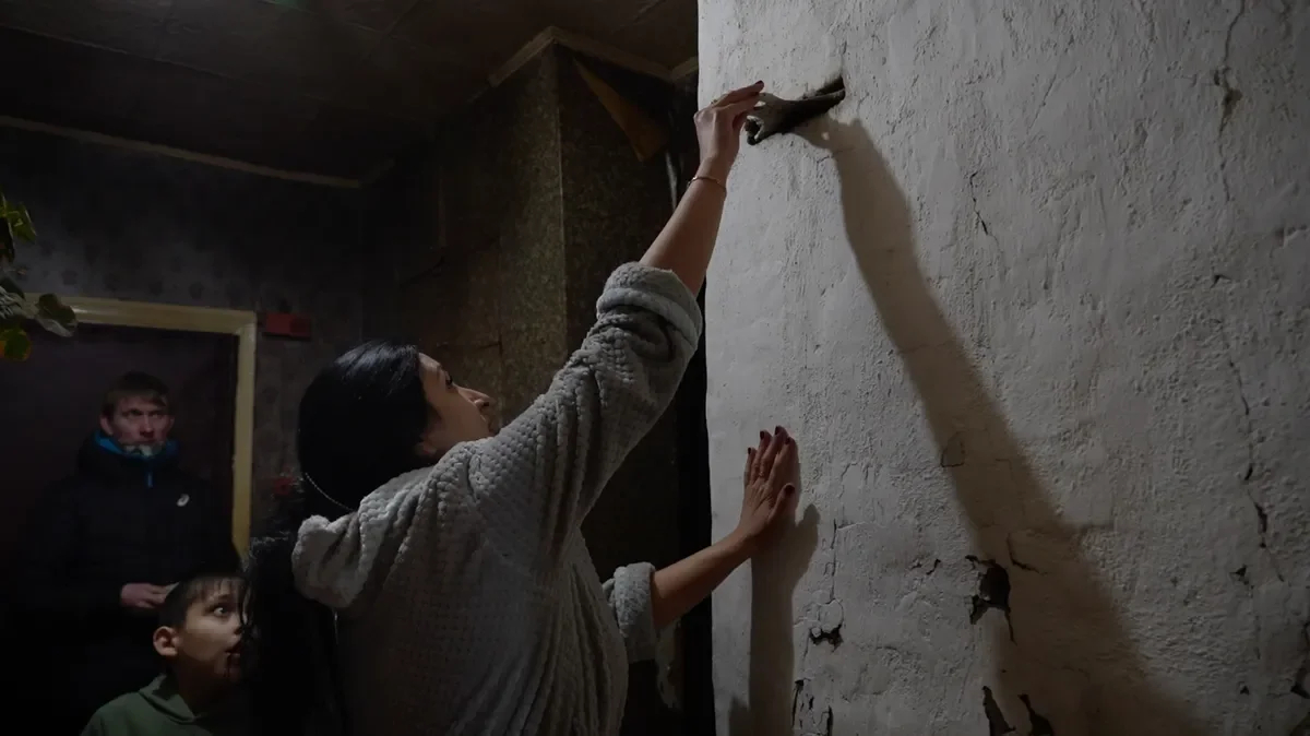 Oksana with her younger son at the stove. <a href="https://www.youtube.com/watch?v=NjrPBmXX3vo" rel="noopener noreferrer" title="https://www.youtube.com/watch?v=NjrPBmXX3vo">A shot from the film “Firewood for the mobilised”</a>
