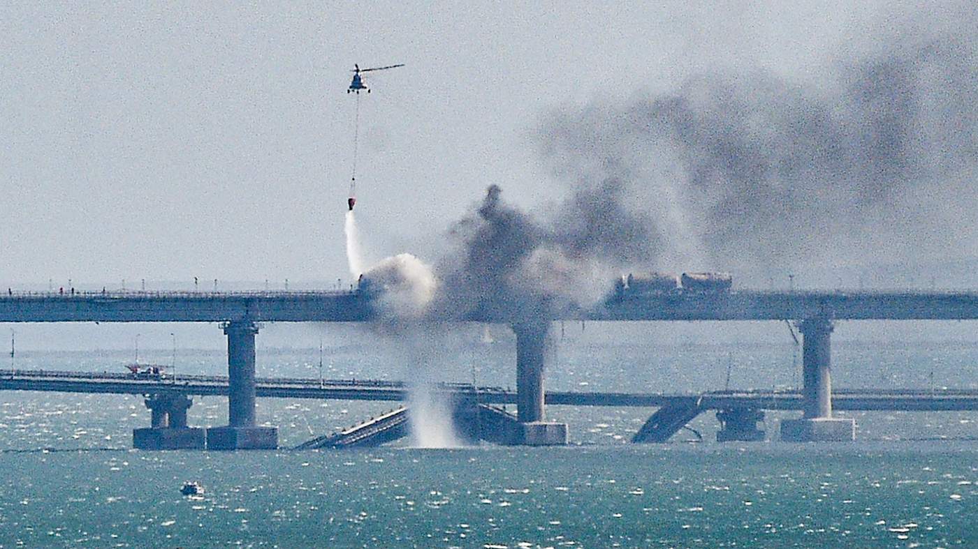 Пожарный вертолет заливает водой огонь на обрушившейся части моста через Керченский пролив в Крыму, 8 октября 2022 года. Фото: EPA