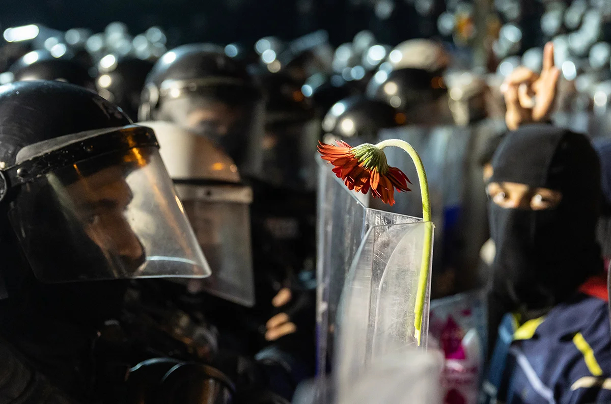 Протестующий прикрепил цветок к щиту полицейского во время акции протеста против задержания мэра Стамбула Экрема Имамоглу в Стамбуле, Турция, 24 марта 2025 года. Фото: Erdem Sahim / EPA-EFE
