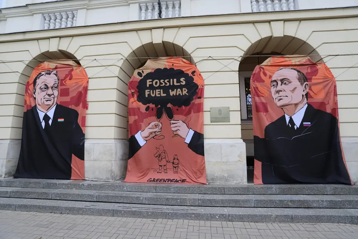Баннер с изображением Виктора Орбана и Владимира Путина и лозунгом «Ископаемые — топливо войны» перед посольством Венгрии в Варшаве, 25 мая 2022 года. Фото:<br>EPA-EFE / ZOFIA BICHNIEWICZ POLAND OUT