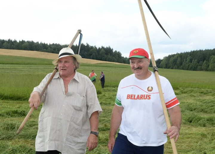 French actor Gérard Depardieu and Alexander Lukashenko carry scythes as they walk through the grounds of the official presidential residence outside Minsk, 22 July 2015. Photo: EPA / ANDREI STASEVICH 