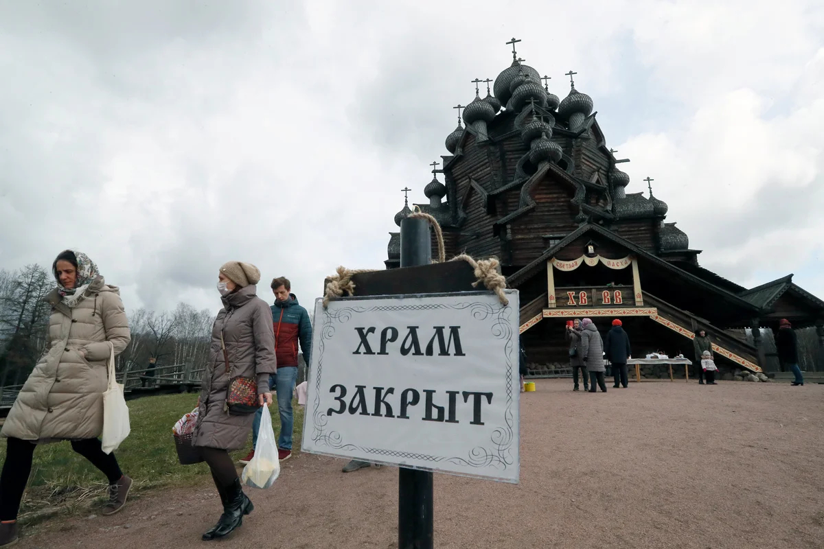 Православные верующие несут пасхальную еду перед православным праздником Пасхи перед закрытым храмом Покрова Божией Матери в Невском лесопарке в Санкт-Петербурге, Россия, 18 апреля 2020 года. Фото: Анатолий Мальцев / EPA-EFE