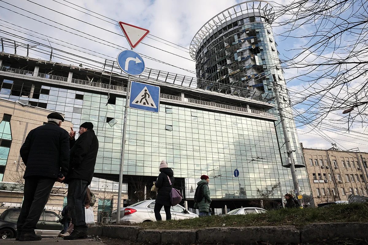 Люди перед поврежденным зданием после обстрела Киева, 29 декабря 2023 года. Фото: Олег Петрасюк / EPA-EFE