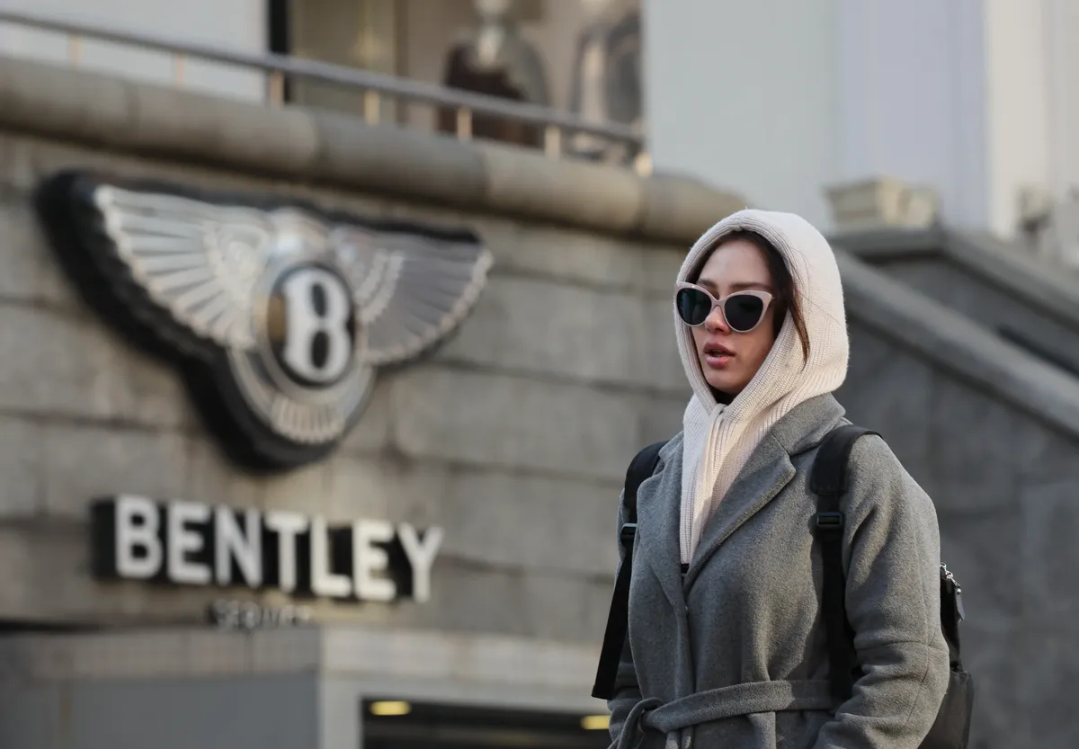 A woman walks past the Bentley logo above a car dealership in central Moscow, 7 February 2025. Photo: EPA-EFE/YURI KOCHETKOV