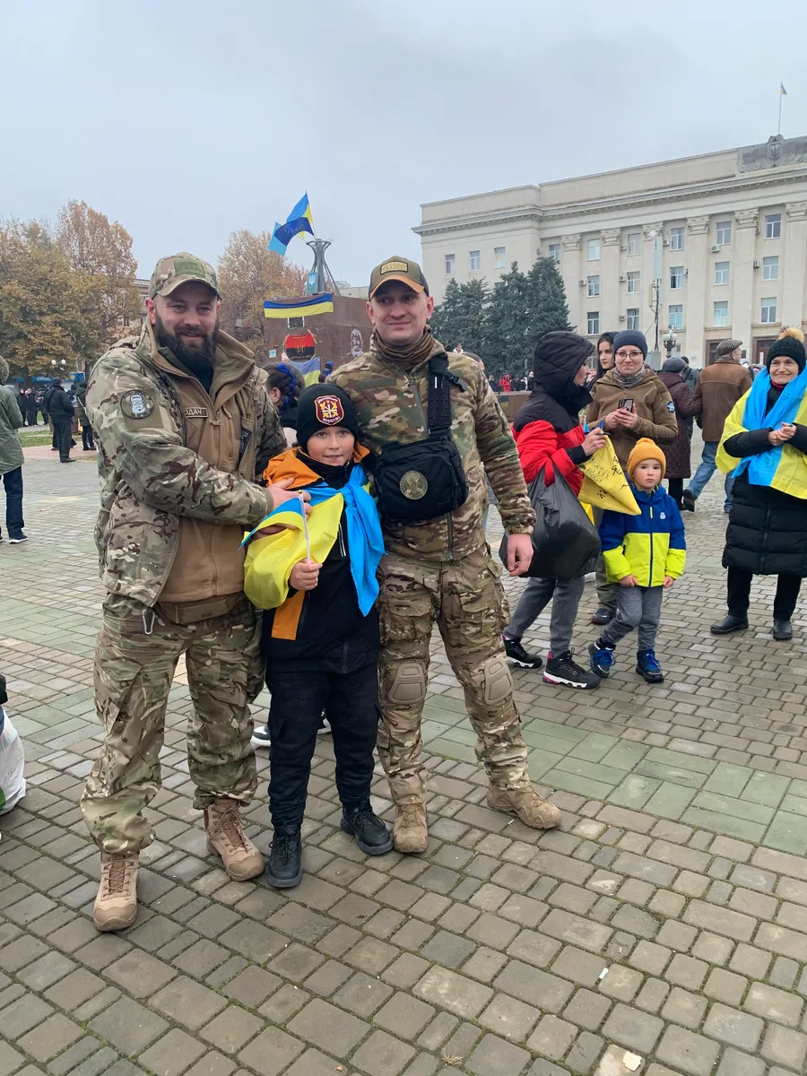 10-летний Максим фотографируется с украинскими военными, они ставят свои автографы на его флаге. Фото: Ольга Мусафирова