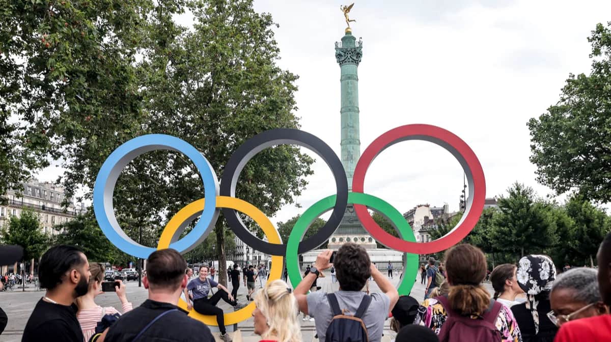Прохожие фотографируются с логотипом Олимпийских игр на площади Бастилии в Париже, Франция, 15 июля 2024 года. Фото: Teresa Suarez / EPA-EFE