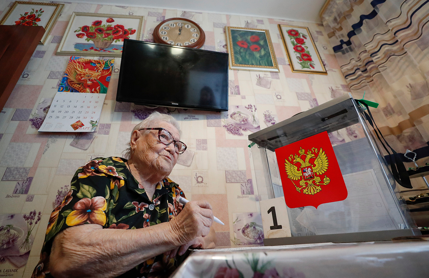 Женщина голосует на президентских выборах у себя дома. Фото: Максим Шипенков / EPA