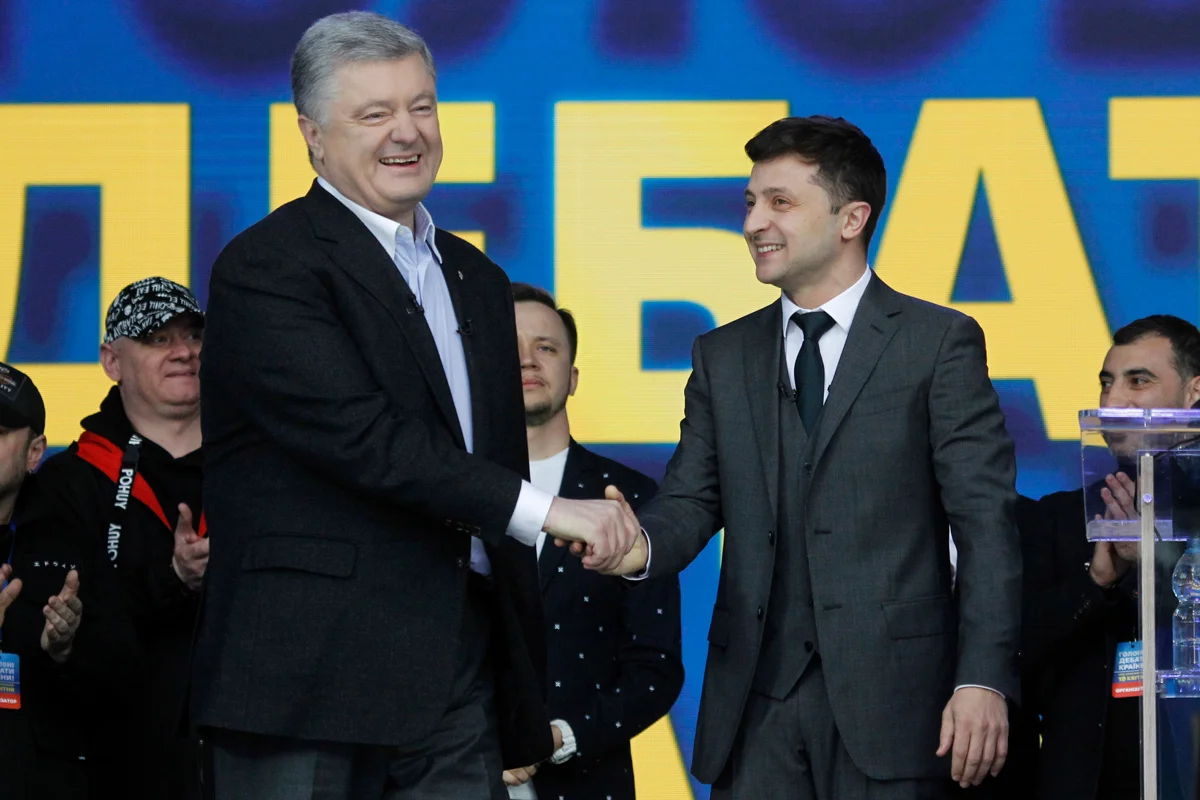 Кандидаты в президенты Петр Порошенко (слева) и Владимир Зеленский (справа) пожимают друг другу руки во время участия в дебатах в Киеве, Украина, 19 апреля 2019 года. Фото: Сергей Долженко / EPA-EFE