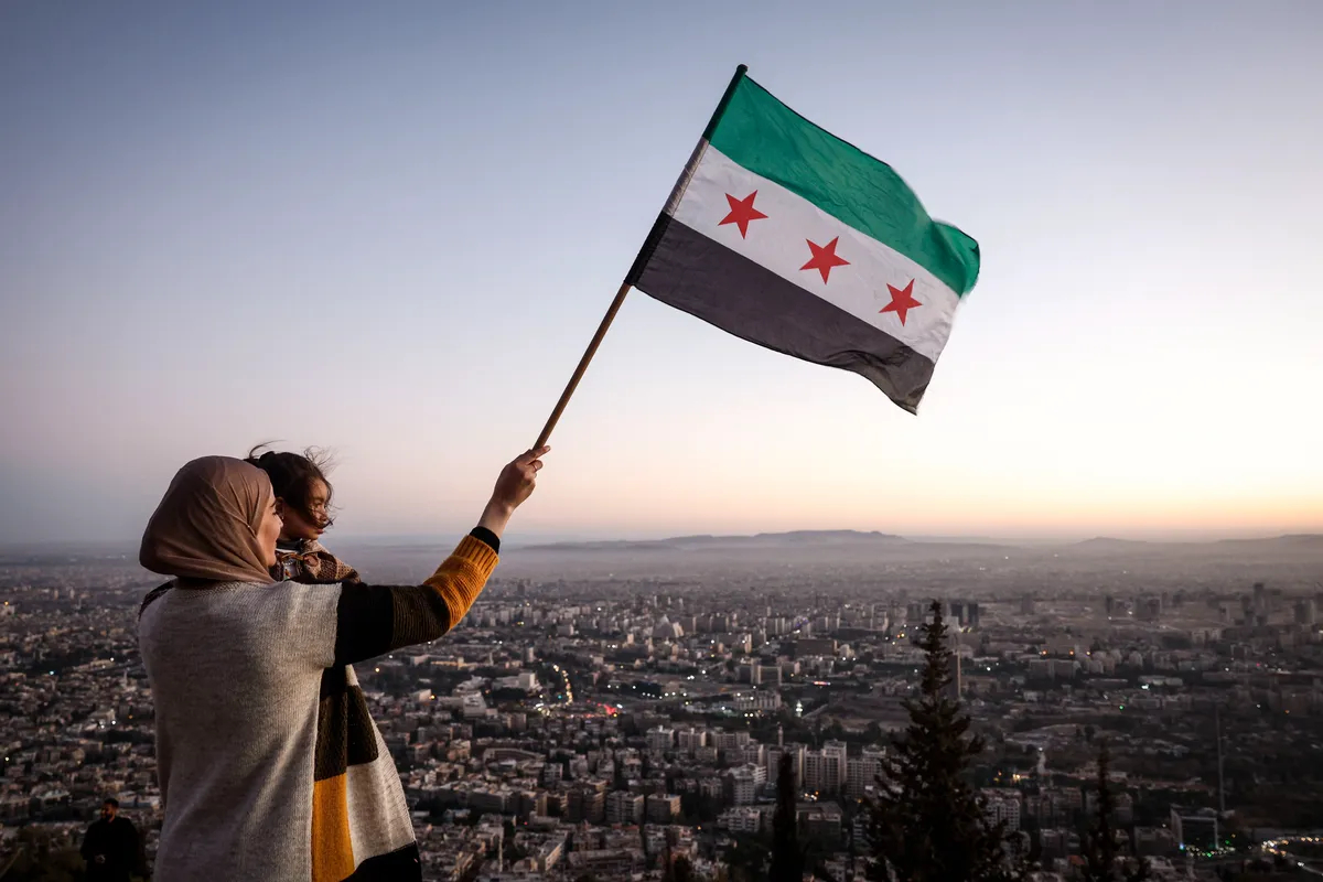 A mother and daughter wave the new Syrian flag over Damascus following the overthrow of Bashar al-Assad, 19 December 2024. Photo: EPA-EFE / ANTONIO PEDRO SANTOS