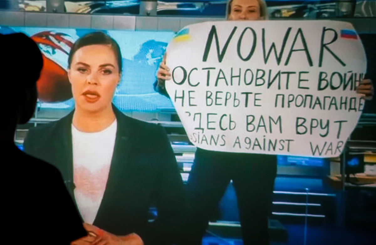Женщина смотрит запись вечернего выпуска новостей Первого канала, в котором Марина Овсянникова появилась с написанным от руки антивоенным плакатом, Москва, Россия, 15 марта 2022 года. Фото: EPA / DSK