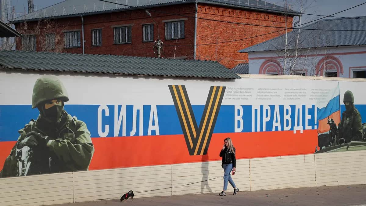 A woman walks her dog past a banner that reads “power is in truth” in the town of Yefremov in Russia’s central Tula region, 6 April 2023. Photo: EPA / Maxim Shipenkov