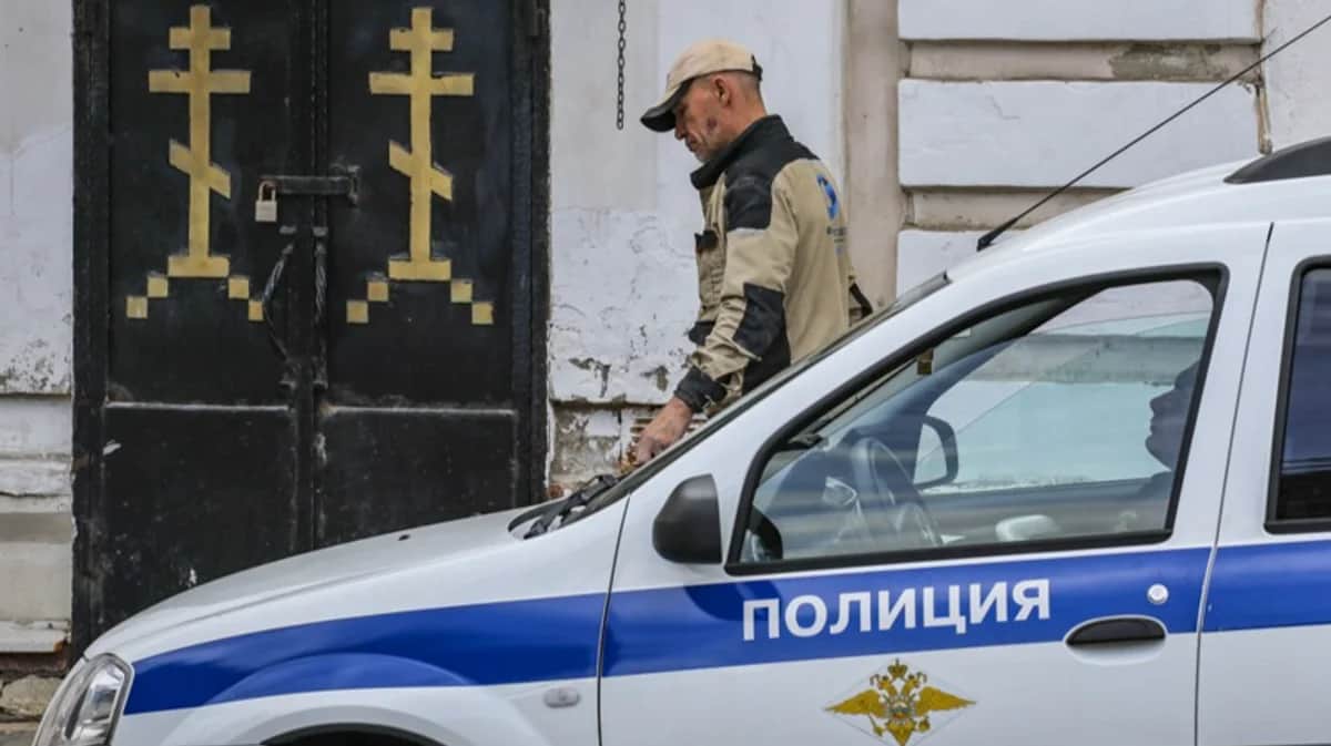 Мужчина проходит мимо полицейской машины, припаркованной возле православной церкви. Фото: Юрий Кочетков / EPA