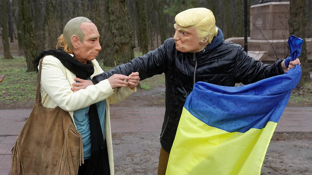 Люди в масках Путина и Трампа держат украинский флаг во время митинга против администрации Трампа и в поддержку украинского и американского народов у здания посольства США в Киеве, 15 марта 2025 года. Фото: Sergey Dolzhenko / EPA-EFE