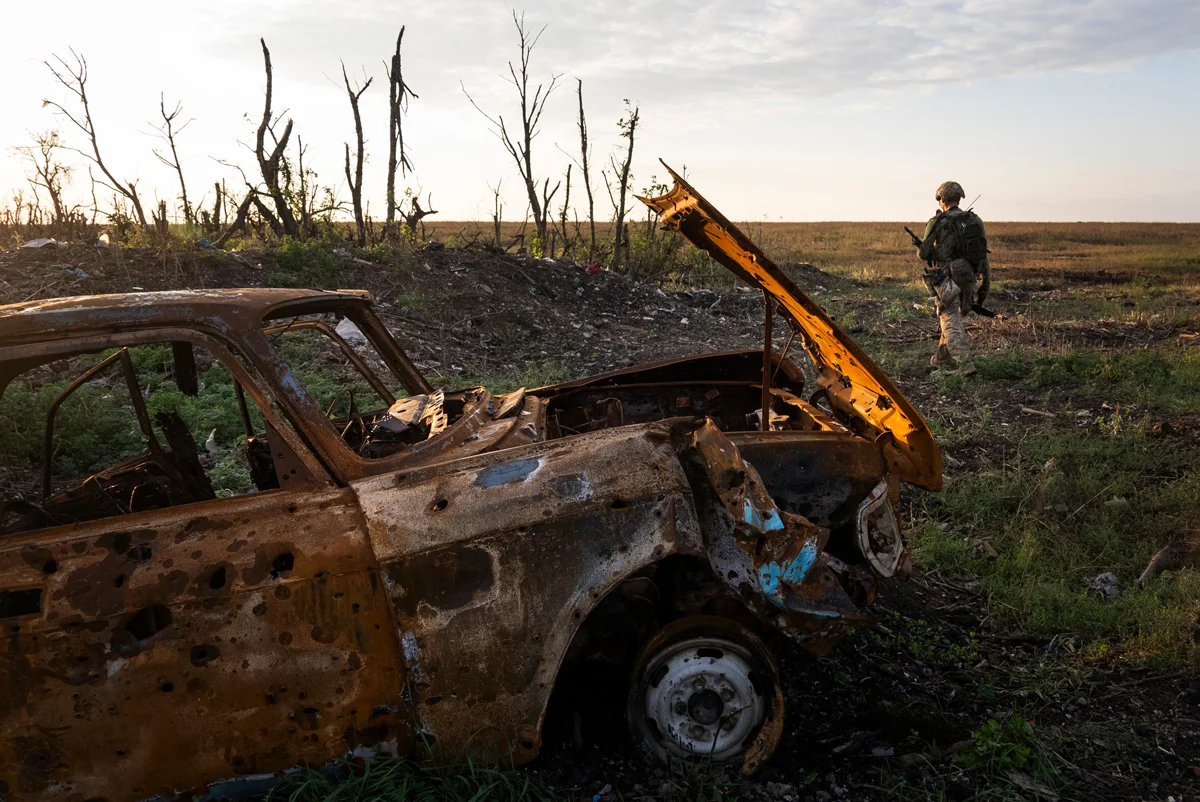 Украинский военный рядом с выжженной машиной у линии фронта в Донецкой области, Украина, 16 сентября 2023 года. Фото: Mstyslav Chernov / Cinetic Media