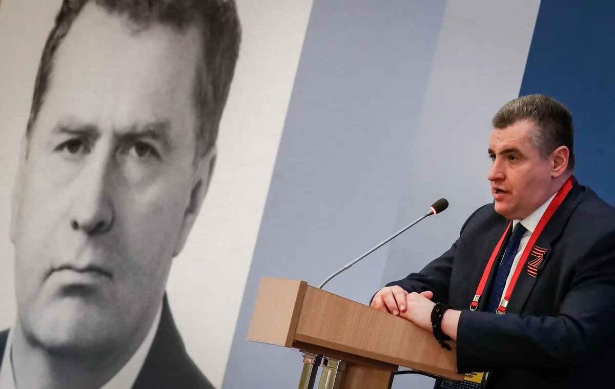 Leonid Slutsky addresses an LDPR congress under the gaze of late party founder Vladimir Zhirinovsky in Moscow on 27 May 2022. Photo: EPA-EFE/YURI KOCHETKOV