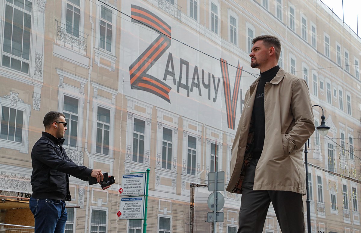 Мужчины около баннера с надписью «Zадачу Vыполним», размещенного на фасаде здания в центре Москвы, Россия, 21 сентября 2022 года. Фото: Максим Шипенков / EPA